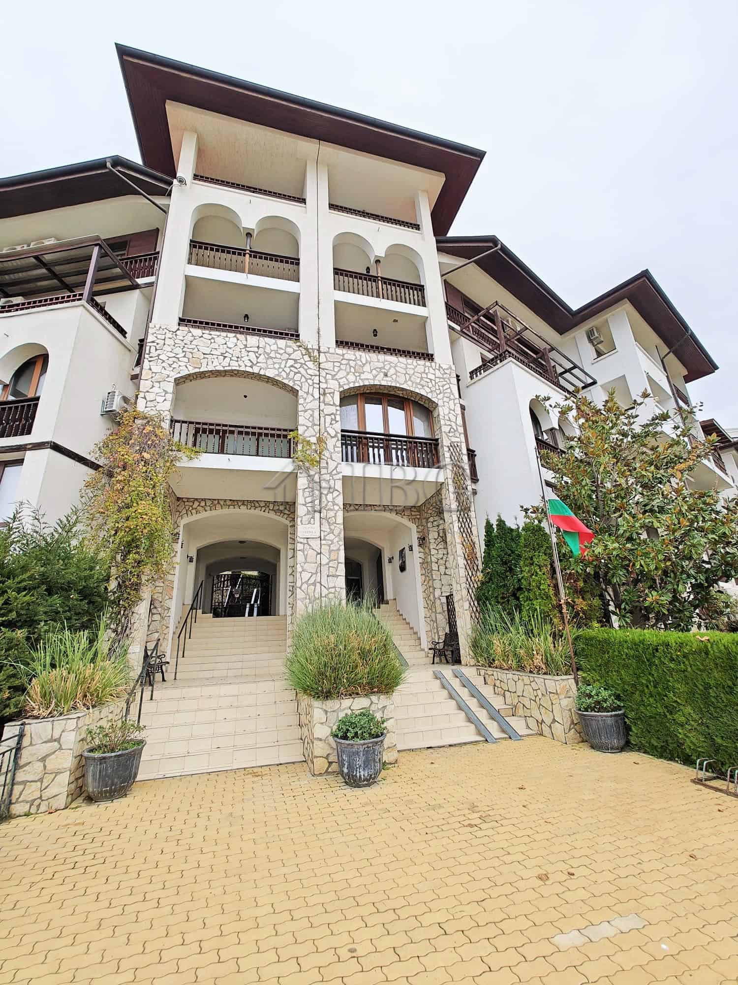 Bright exterior of a modern apartment complex with multiple balconies and stone accents, located nea.