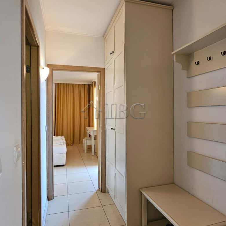 Hallway of a modern apartment with wardrobe, hooks, and entryway furniture in a sunny beach location.