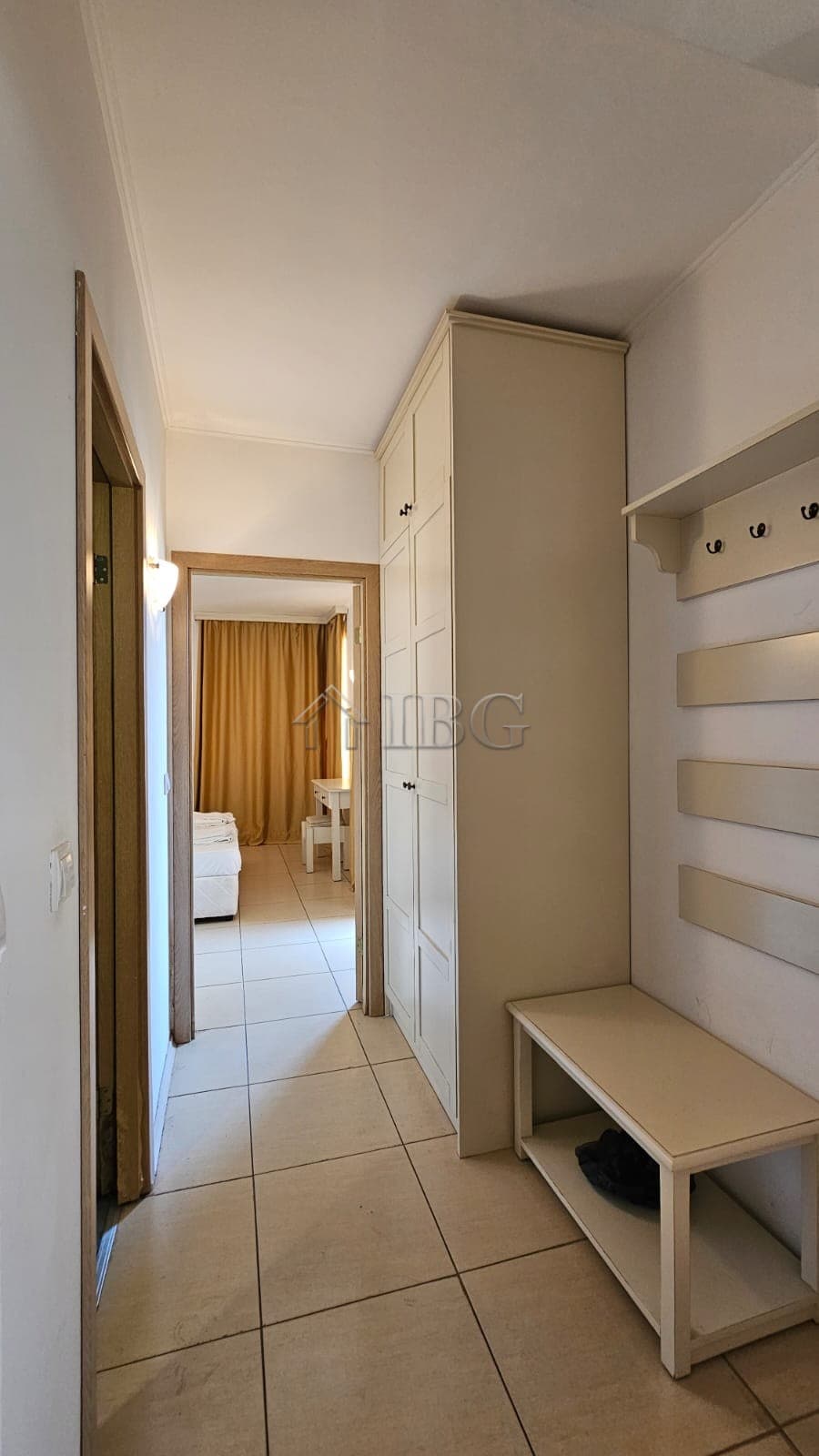 Hallway of a modern apartment with wardrobe, hooks, and entryway furniture in a sunny beach location.