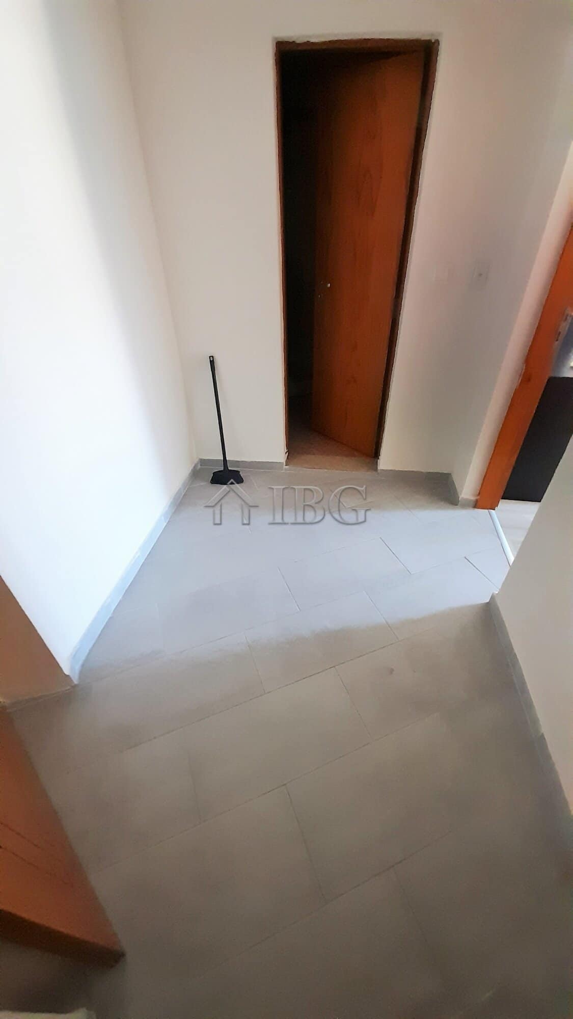 Interior view of a renovated apartment entrance with a door and cleaning tool.