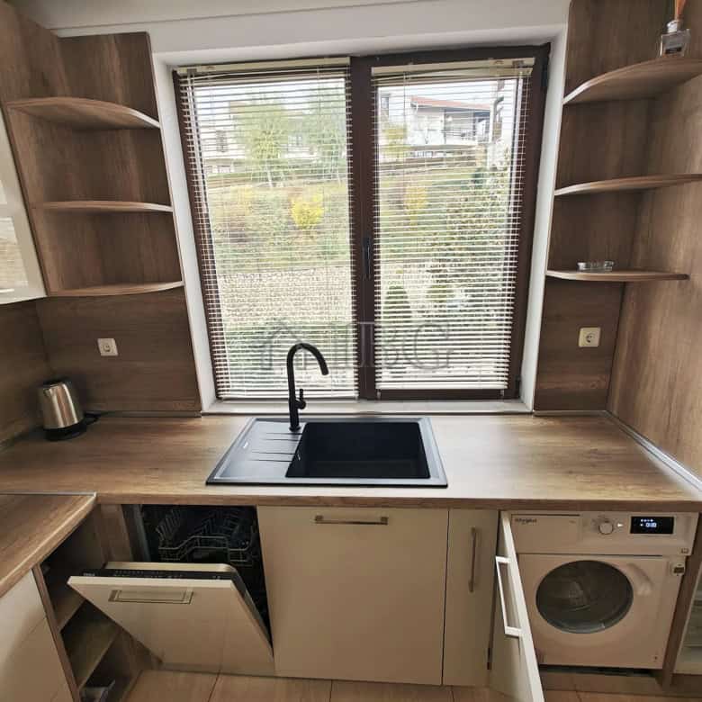 Modern kitchen with large window, black sink, and open wooden shelves.