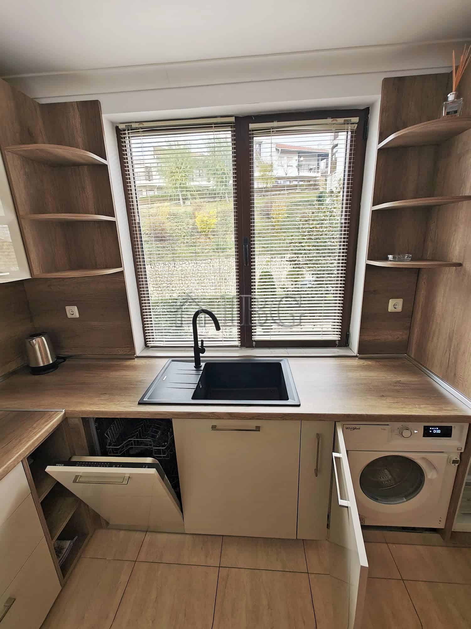 Modern kitchen with large window, black sink, and open wooden shelves.