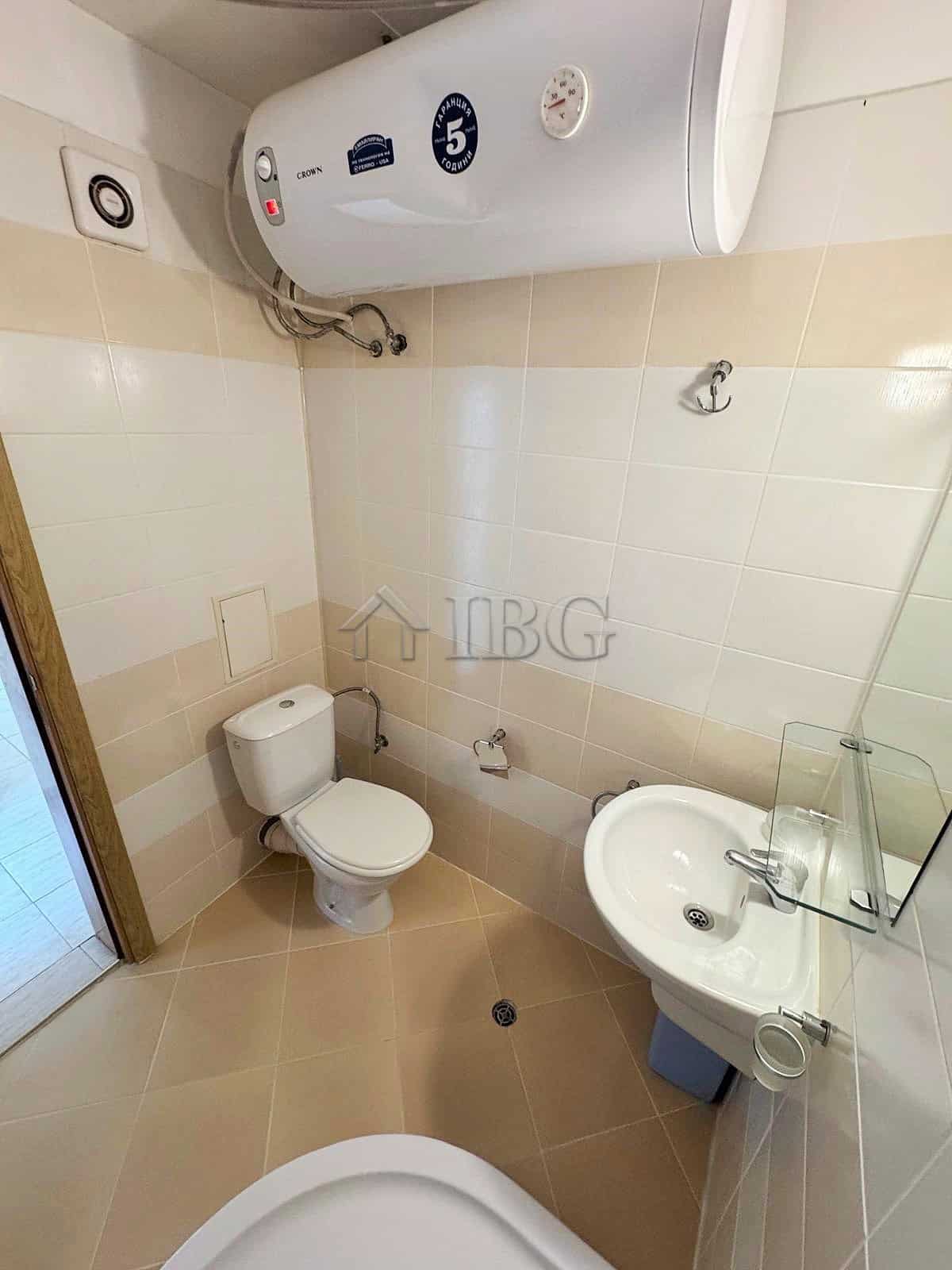Modern bathroom with water heater and basic fixtures at Pollo Resort, Sunny Beach. Clean, compact bathroom with water heater, toilet, and sink for comfortable living.