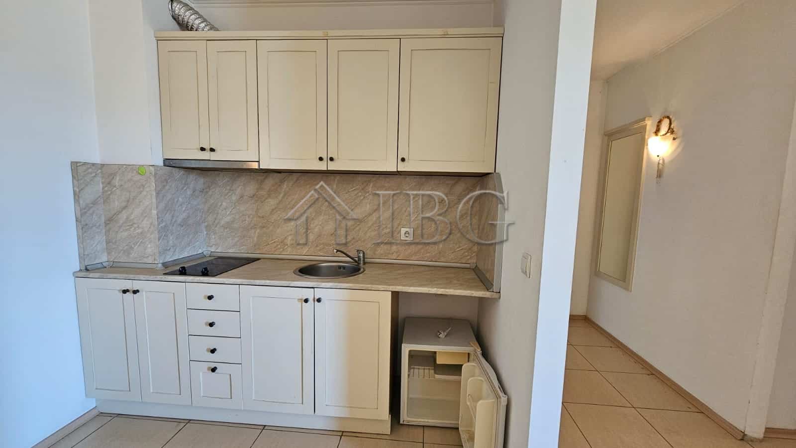 Modern kitchen with white cabinets and marble backsplash in Tria Apartments, Sunny Beach.