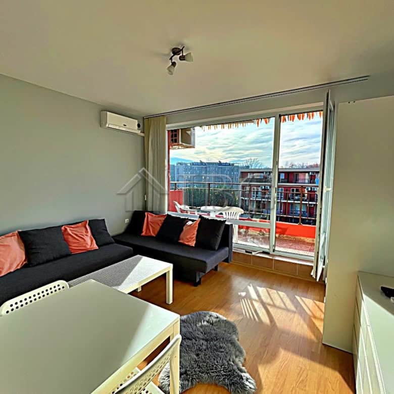 Bright living space featuring a sofa, large windows, and access to a balcony overlooking the pool.