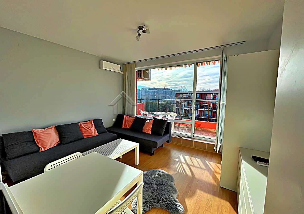 Bright living space featuring a sofa, large windows, and access to a balcony overlooking the pool.