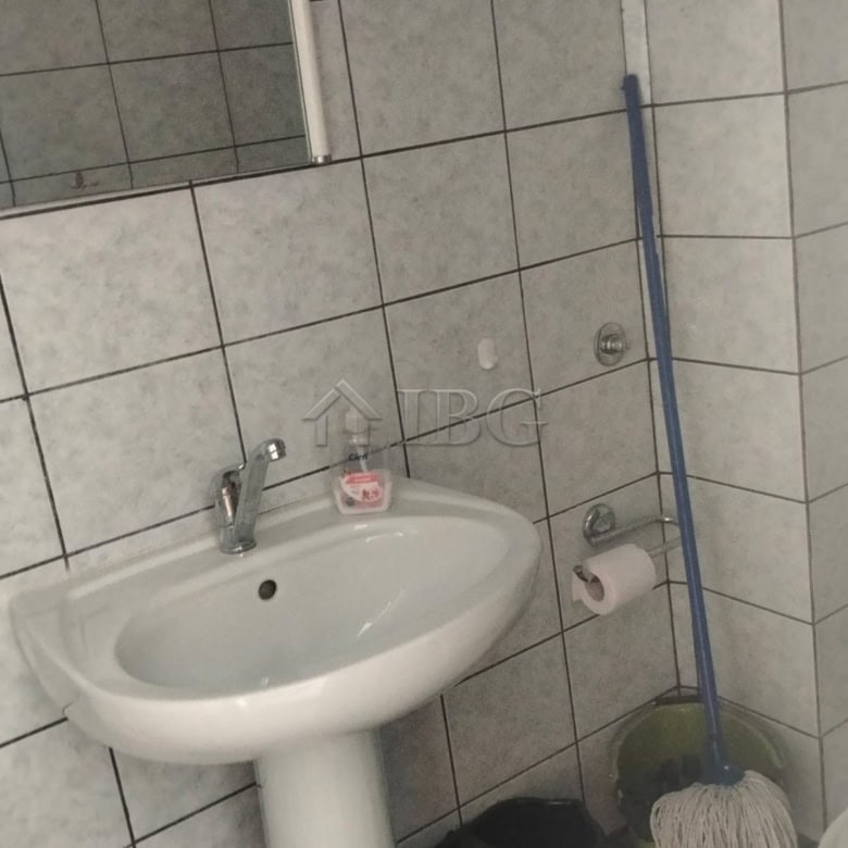 Bright bathroom with sink, mirror, and cleaning supplies.