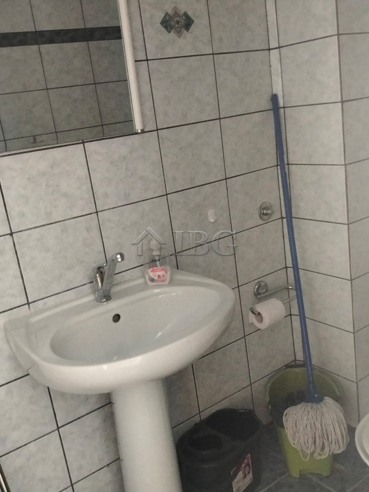 Bright bathroom with sink, mirror, and cleaning supplies.