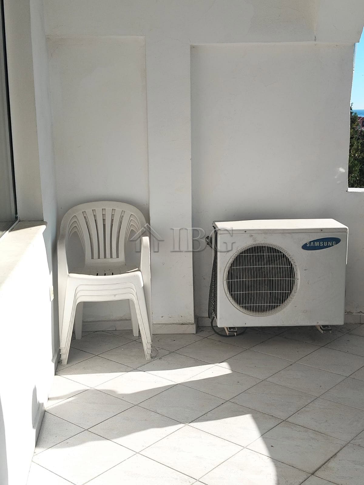 Balcony with plastic chair and air conditioning unit overlooking Sveti Vlas sea view.