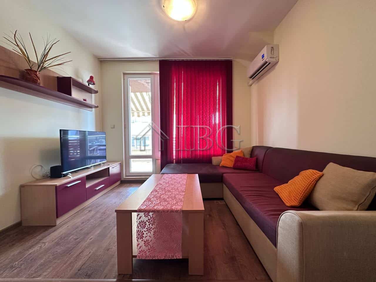 Bright living room with sofa, TV, and balcony in Ravda apartment.