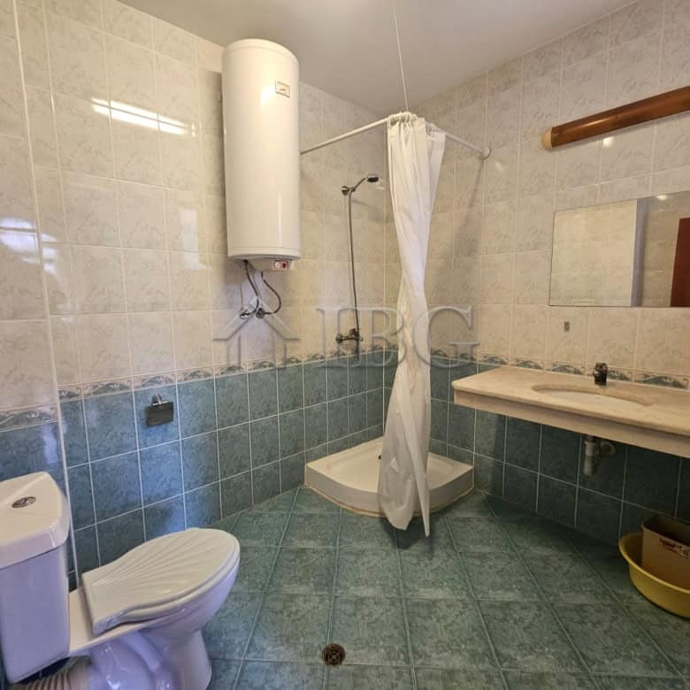 Bathroom with shower, toilet, and sink in a spacious apartment.