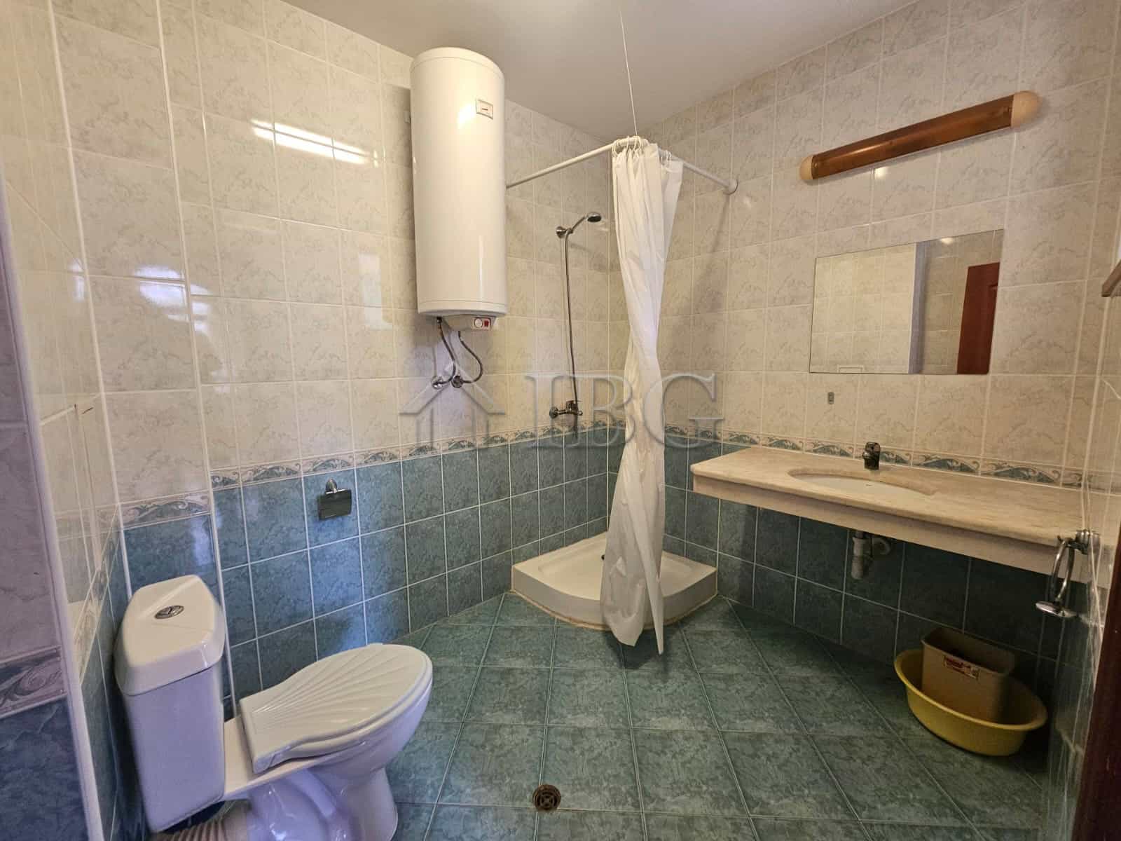 Bathroom with shower, toilet, and sink in a spacious apartment.