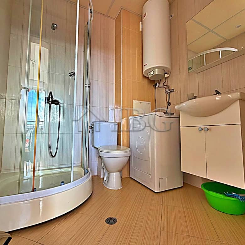 Bright bathroom with shower, toilet, and sink in a modern studio.