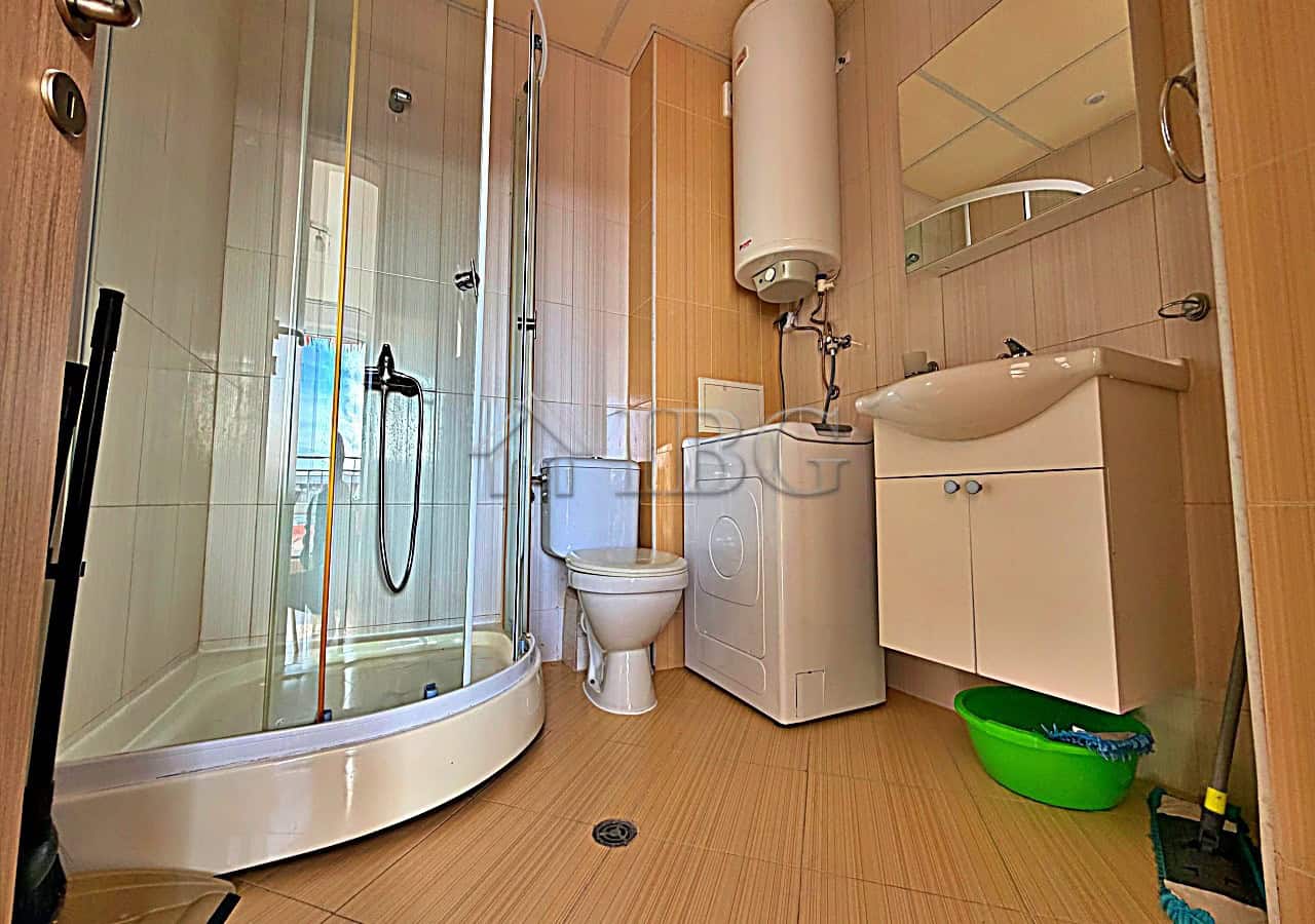 Bright bathroom with shower, toilet, and sink in a modern studio.