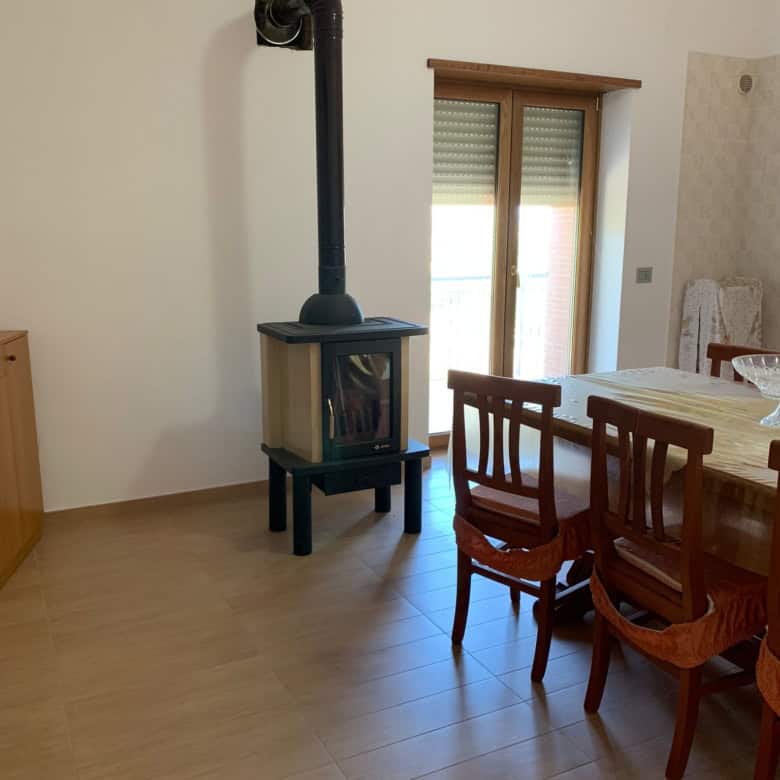 Interior of a 3-bedroom house in Orsara di Puglia with a wood stove and dining area.