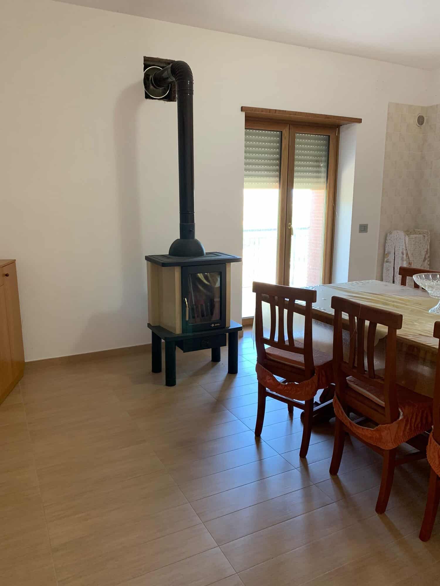 Interior of a 3-bedroom house in Orsara di Puglia with a wood stove and dining area.