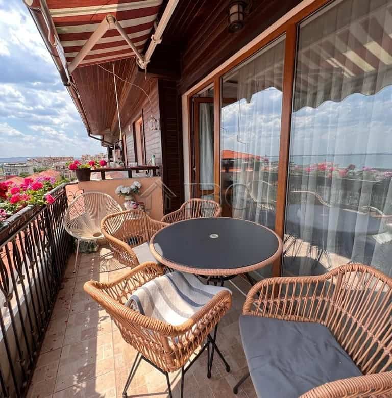 Balcony with panoramic sea views in Sveti Vlas, featuring outdoor seating and vibrant flower arrange.