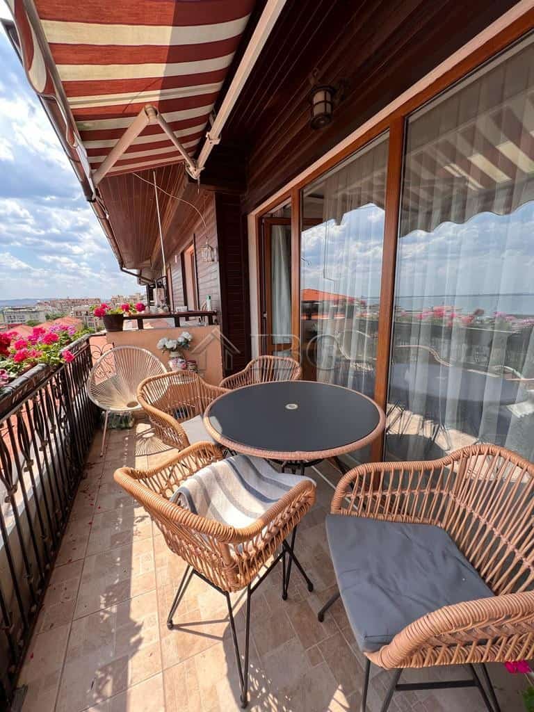 Balcony with panoramic sea views in Sveti Vlas, featuring outdoor seating and vibrant flower arrange.