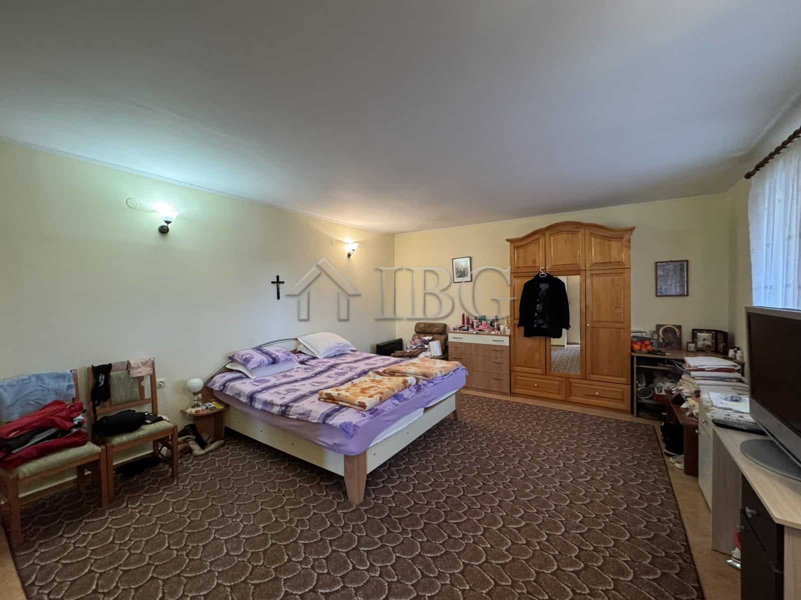 Bright bedroom with large bed and wooden wardrobe in Kosharitsa property.