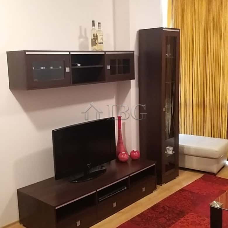 Modern living room with TV, wall-mounted shelves, and a tall glass cabinet.