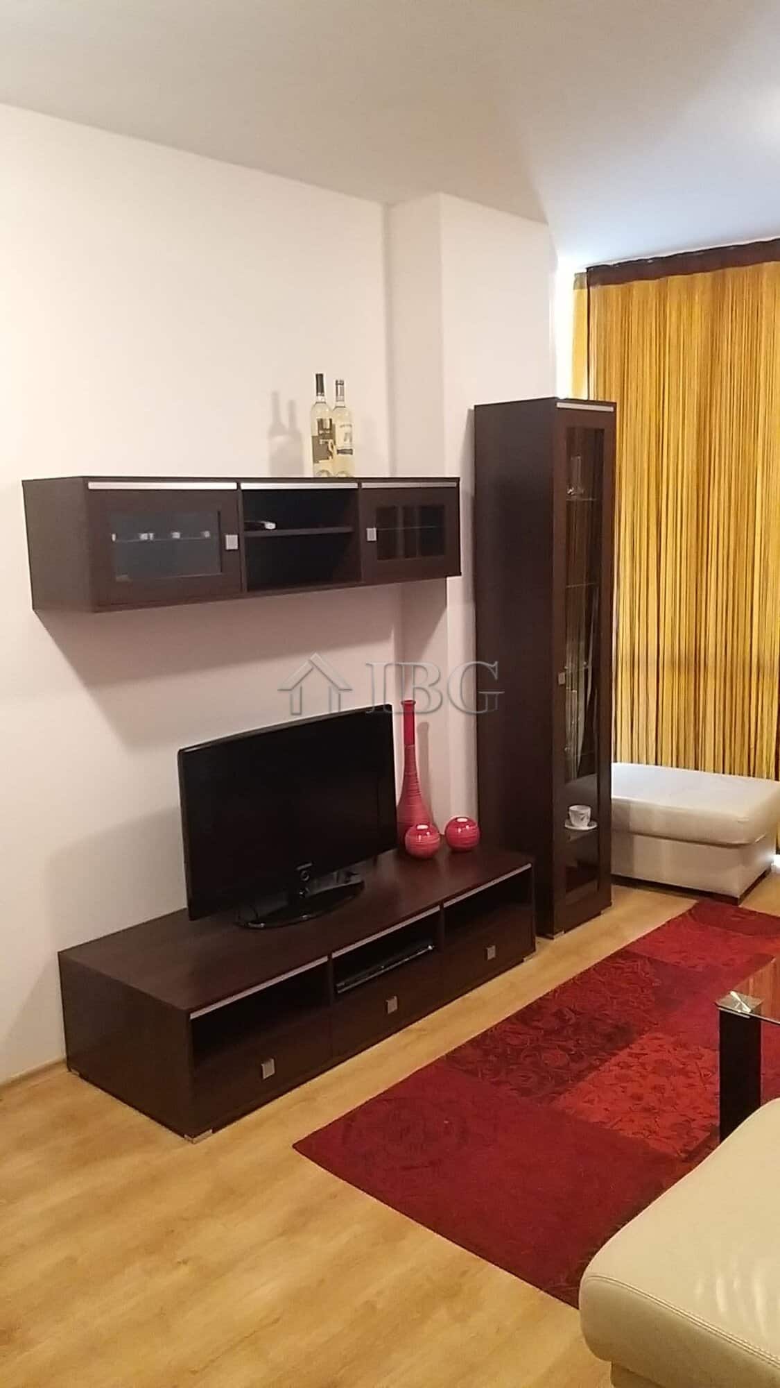 Modern living room with TV, wall-mounted shelves, and a tall glass cabinet.