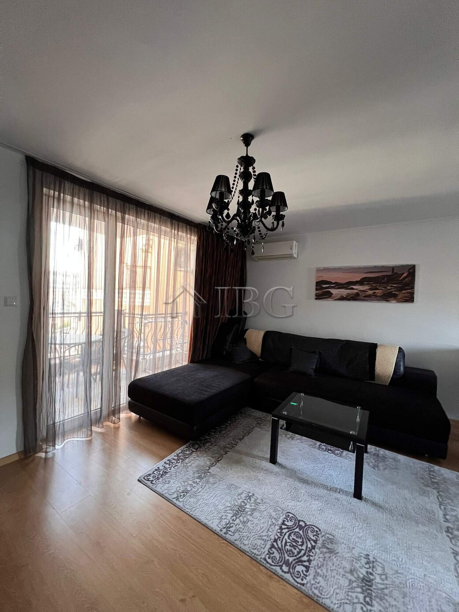 Modern living room with black sofa, chandelier, and panoramic sea views in Sveti Vlas apartment.