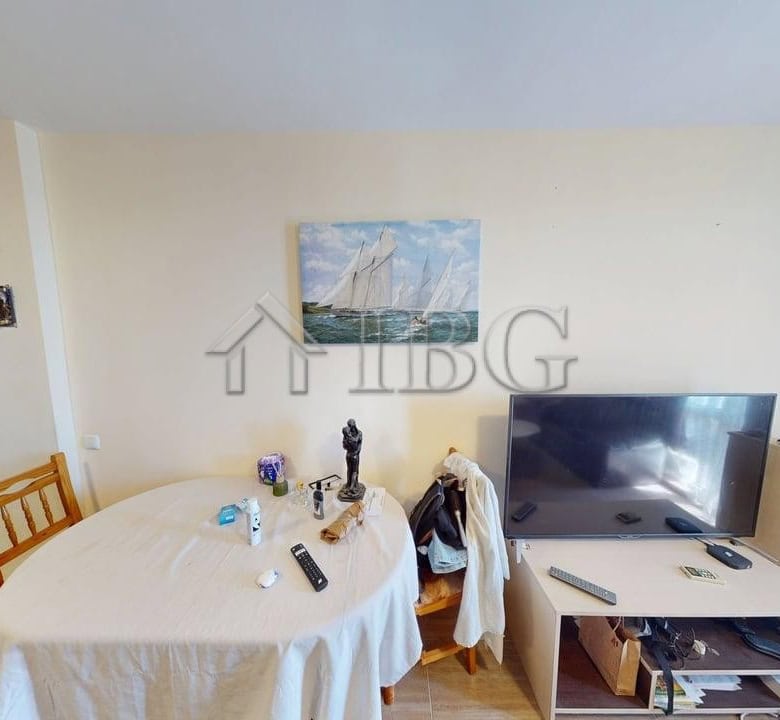 Bright living room with TV, dining table, and decor in Kosharitsa apartment complex.