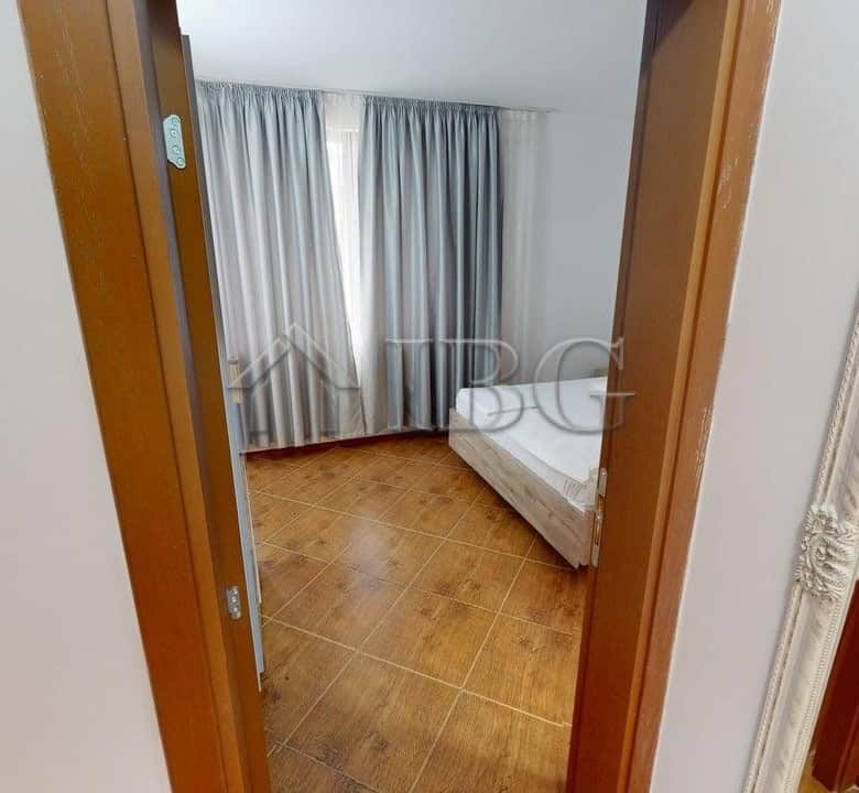 Interior view of a bedroom in Bay View Villas, Kosharitsa, with a bed and large window with curtains.