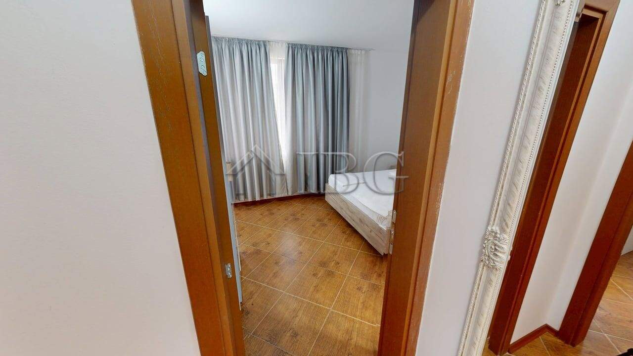 Interior view of a bedroom in Bay View Villas, Kosharitsa, with a bed and large window with curtains.