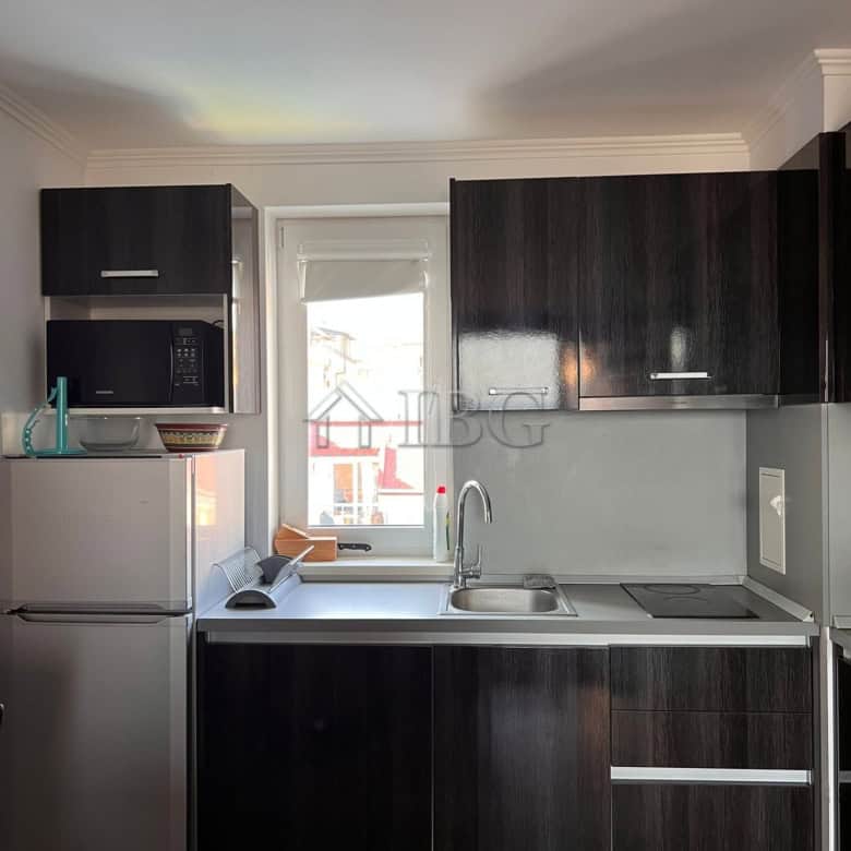 Compact kitchen with dark cabinets, microwave, and window view in Sveti Vlas apartment.