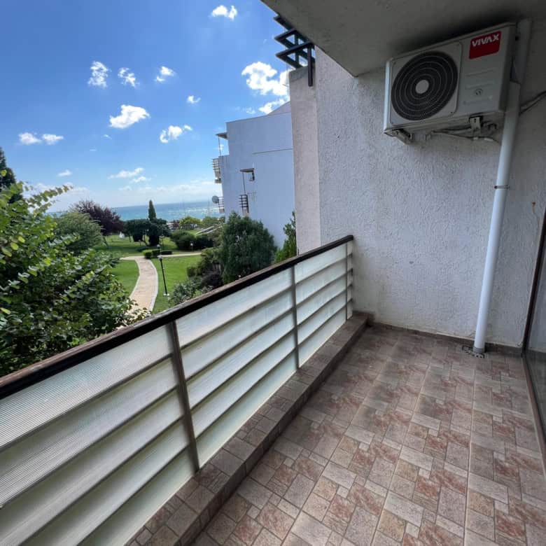 Balcony with air conditioning unit overlooking lush greenery and distant sea in Sveti Vlas.