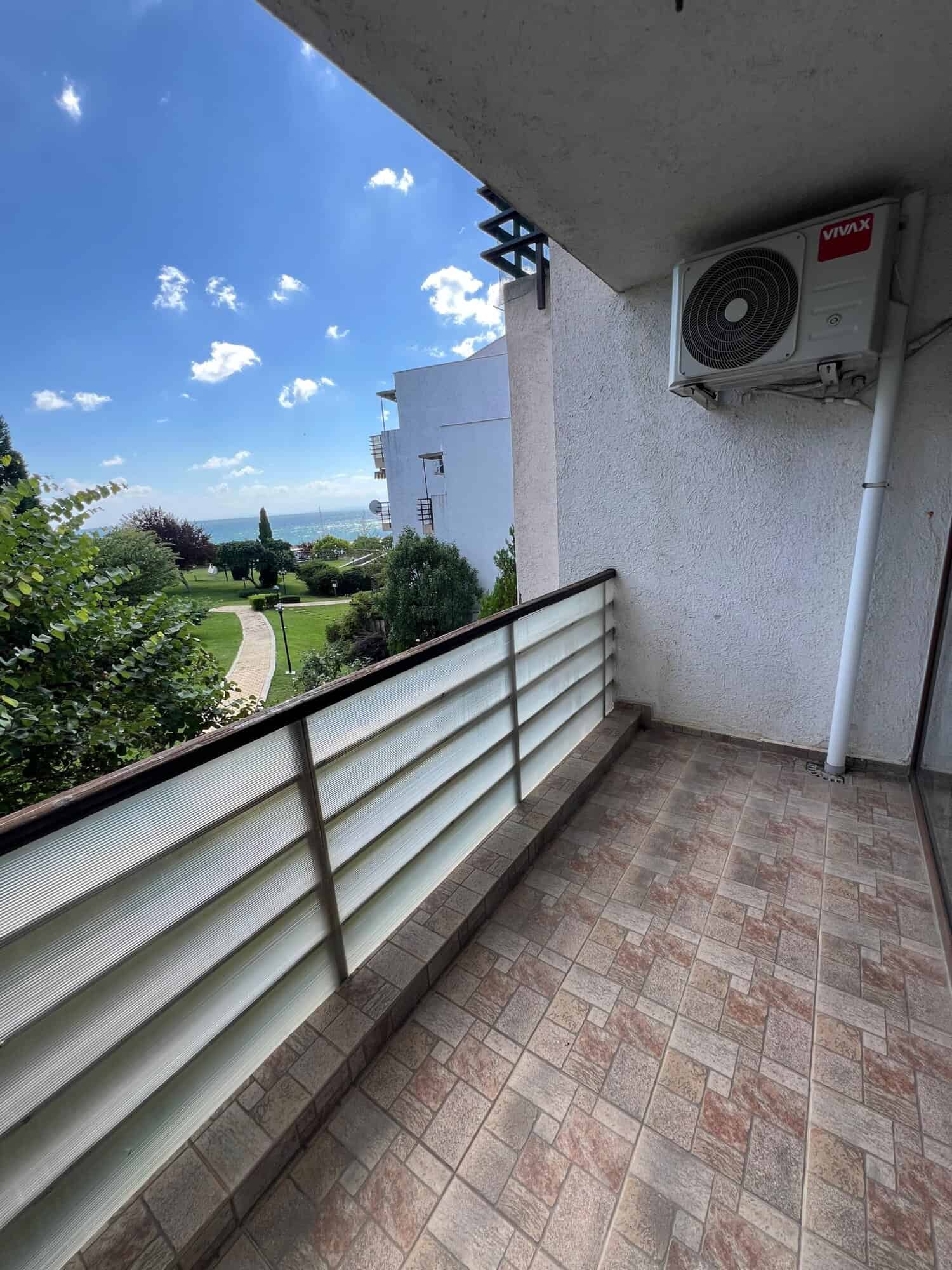 Balcony with air conditioning unit overlooking lush greenery and distant sea in Sveti Vlas.