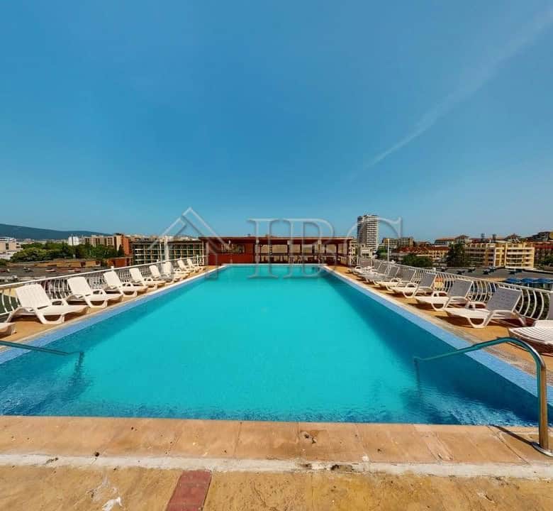 Pool at Barco Del Sol Complex in Sunny Beach, Bulgaria with sun loungers and city view.