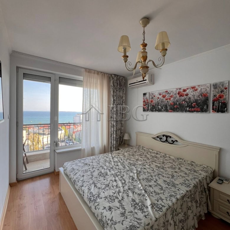 Bright bedroom with large window overlooking the sea and balcony.
