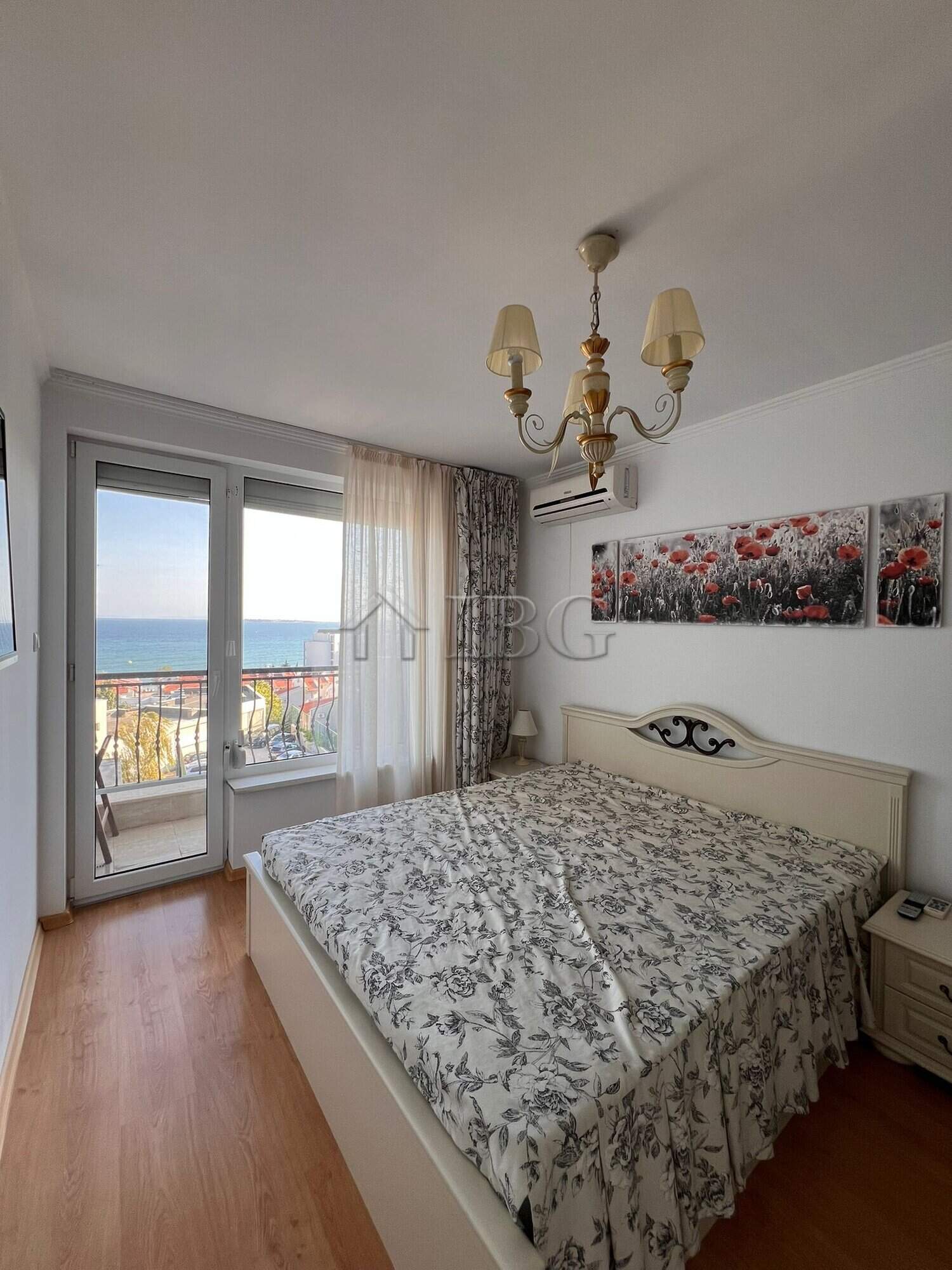 Bright bedroom with large window overlooking the sea and balcony.