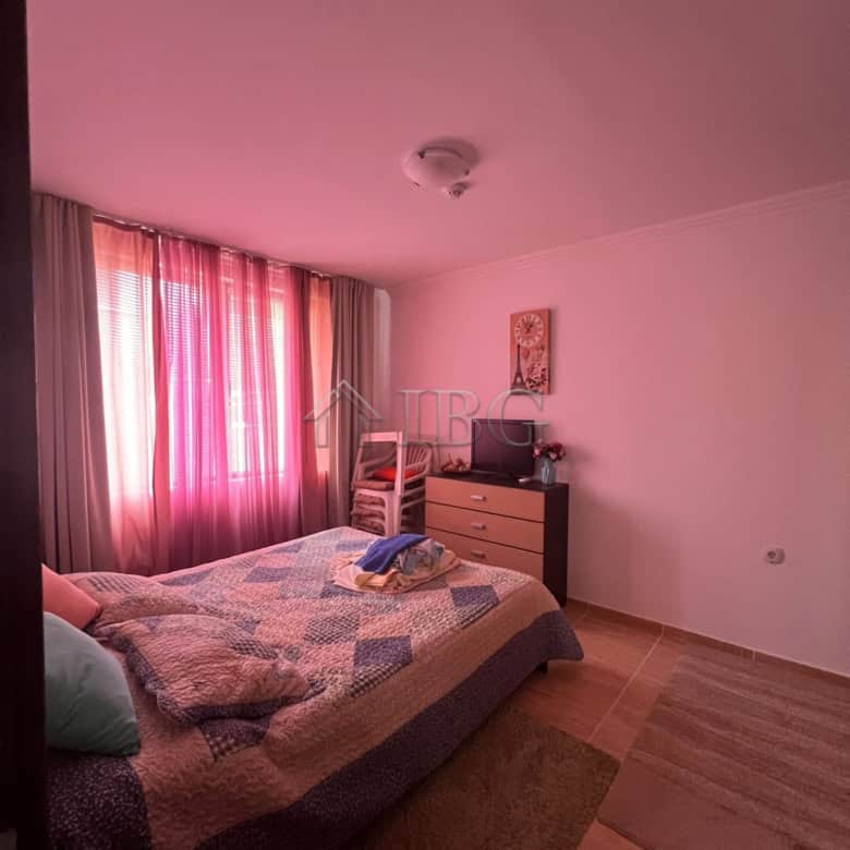 Bright bedroom featuring large windows with pink curtains overlooking the sea and pool in Kambani 3.