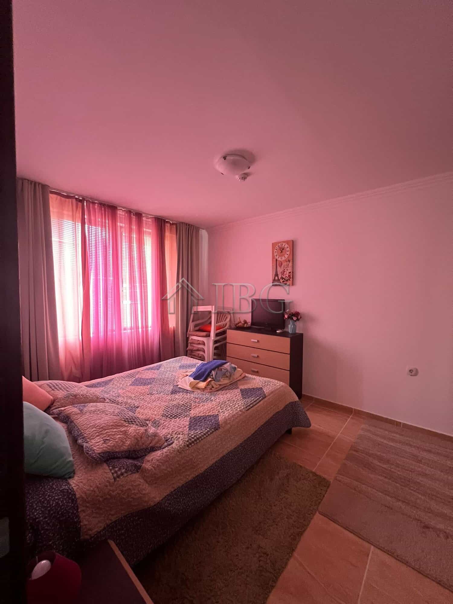 Bright bedroom featuring large windows with pink curtains overlooking the sea and pool in Kambani 3.