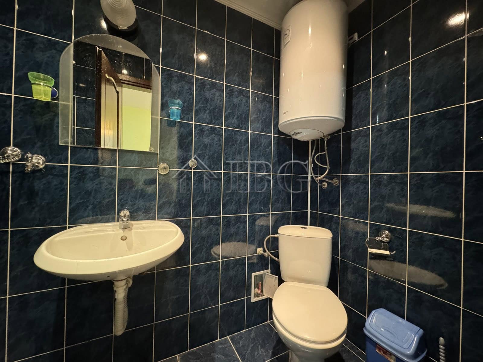 Bright bathroom with modern fixtures and dark tiled walls in Kosharitsa property.