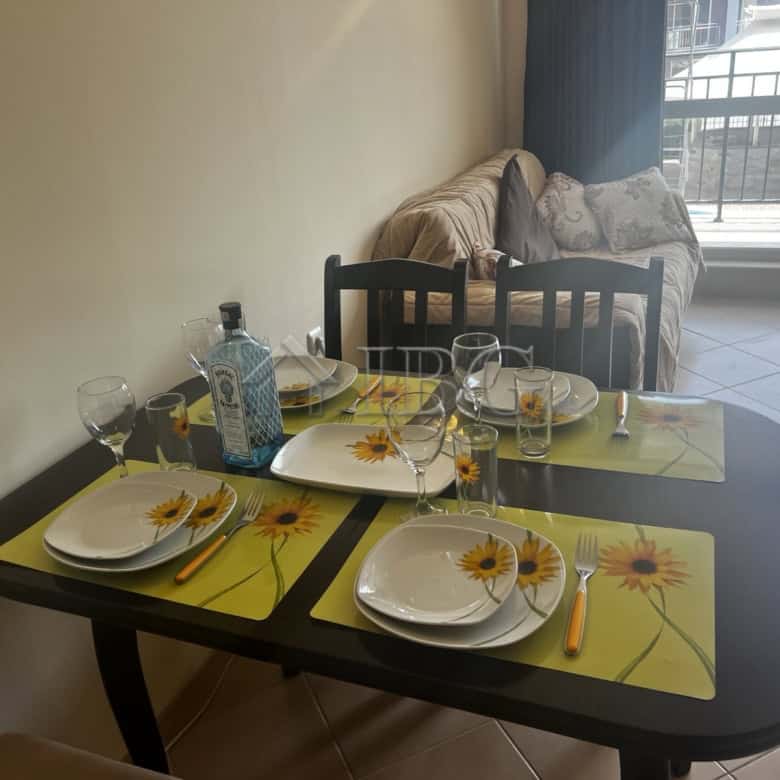 Bright dining area with table set for four, overlooking pool and balcony in Sunset Beach 3.