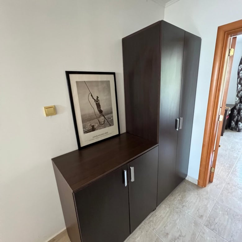 Dark wood storage cabinet in a modern apartment hallway.