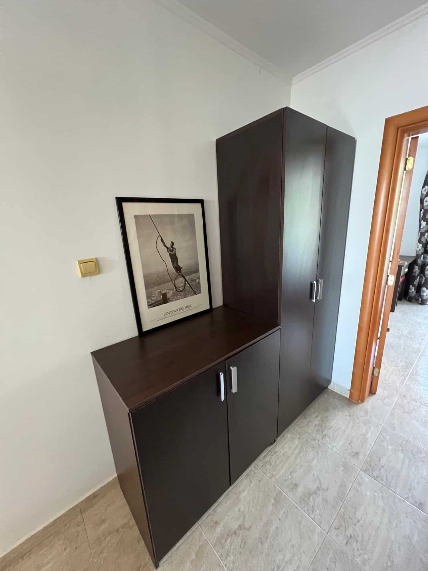 Dark wood storage cabinet in a modern apartment hallway.