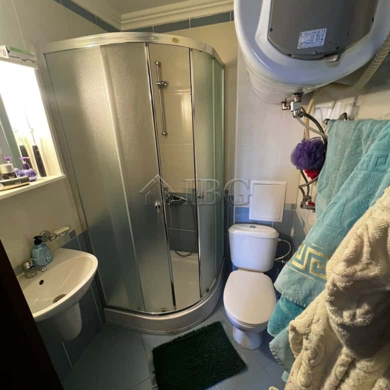 Compact bathroom with shower enclosure, toilet, and washing machine in a modern apartment.