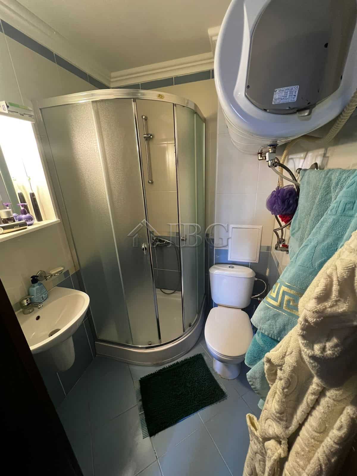 Compact bathroom with shower enclosure, toilet, and washing machine in a modern apartment.