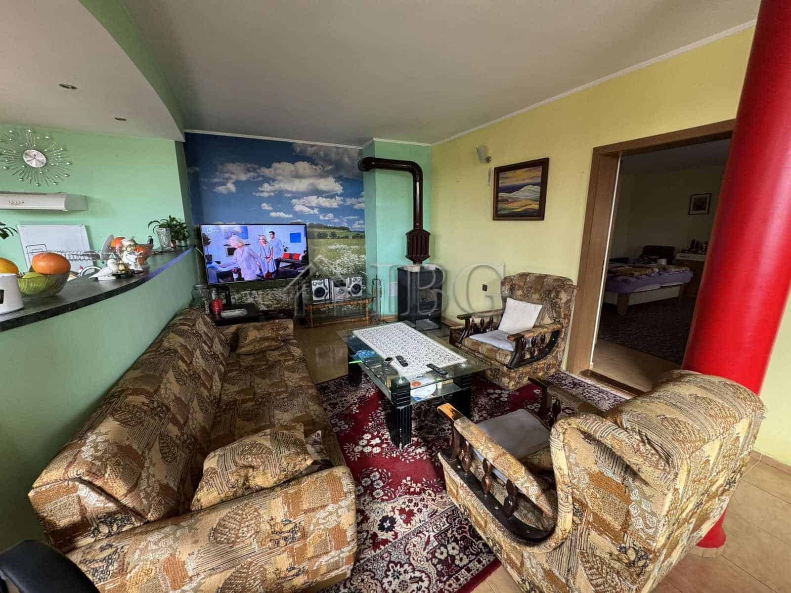 Spacious living area with comfortable sofas, a TV, and colorful decor in a four-story house in Kosha.