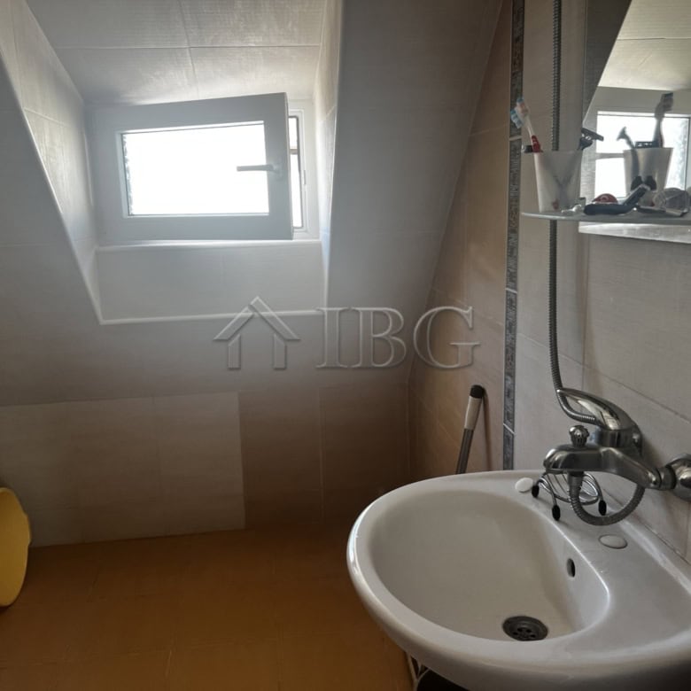 Interior of a small bathroom in a seaside apartment with a window and basic fixtures.