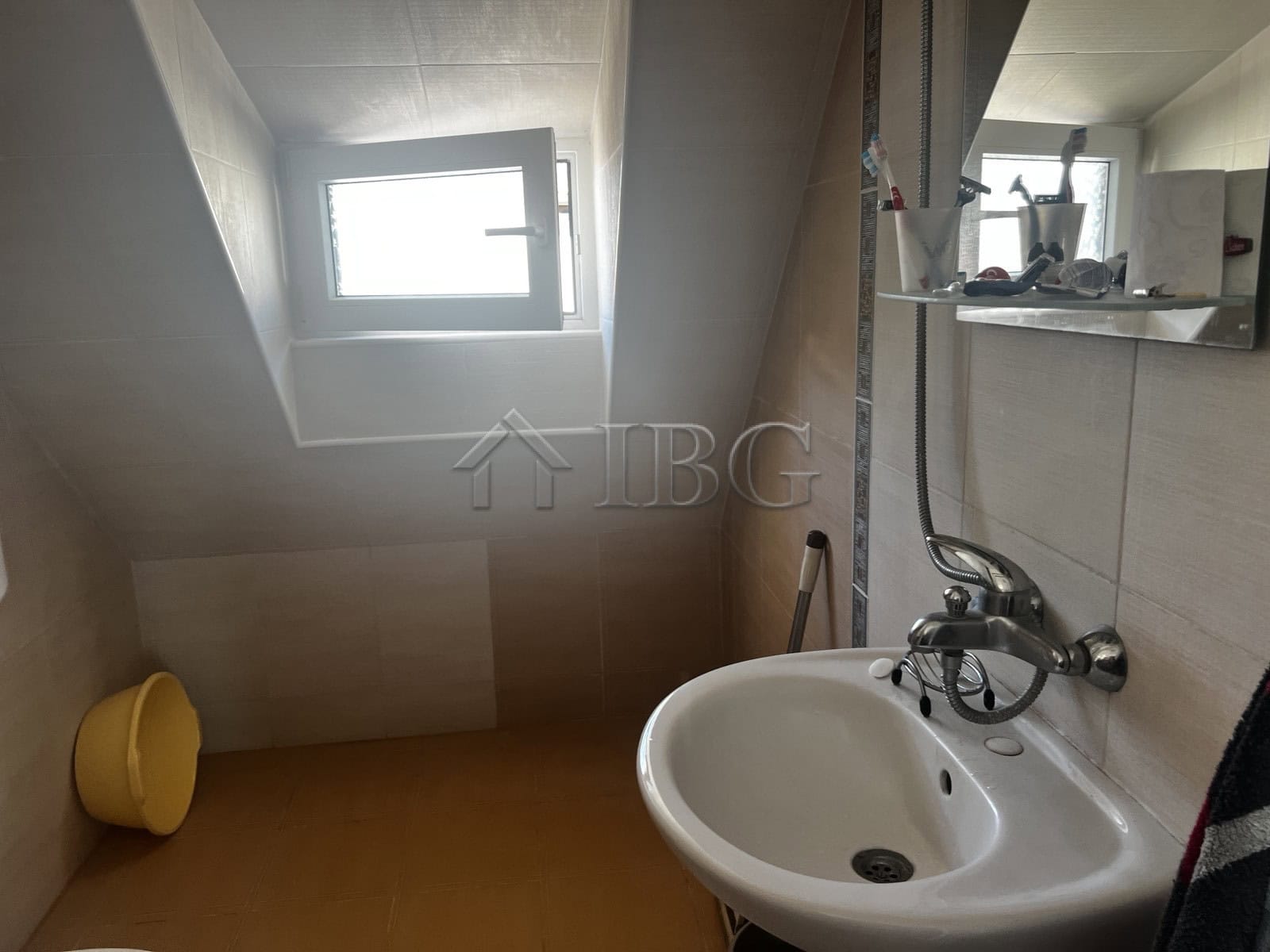 Interior of a small bathroom in a seaside apartment with a window and basic fixtures.