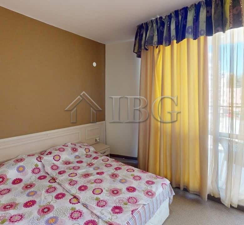 Bedroom with colorful floral bedding and large window with yellow and blue curtains.