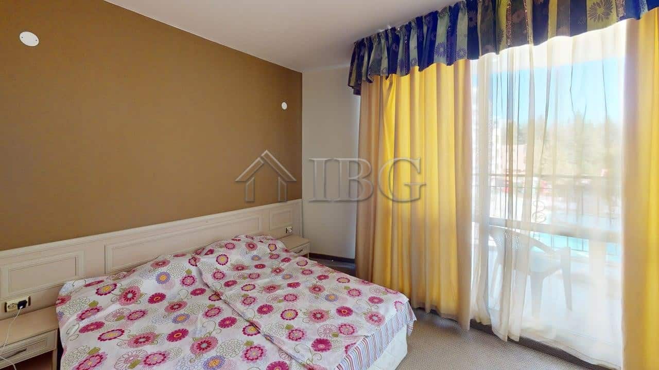 Bedroom with colorful floral bedding and large window with yellow and blue curtains.