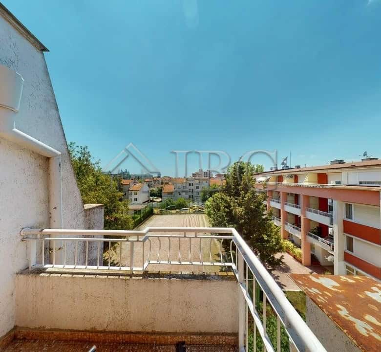 Sunny Beach apartment balcony overlooking residential buildings and lush greenery under a clear blue.