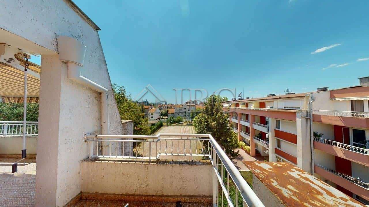 Sunny Beach apartment balcony overlooking residential buildings and lush greenery under a clear blue.